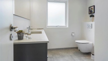 Badeværelse med væghængt toilet og gråt badeværelsesmøbel Badeværelse med væghængt toilet og gråt badeværelsesmøbel