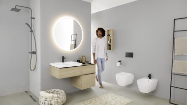 Man walks into the bathroom with washbasin, WC, bidet and bathroom furniture from the Geberit iCon bathroom series