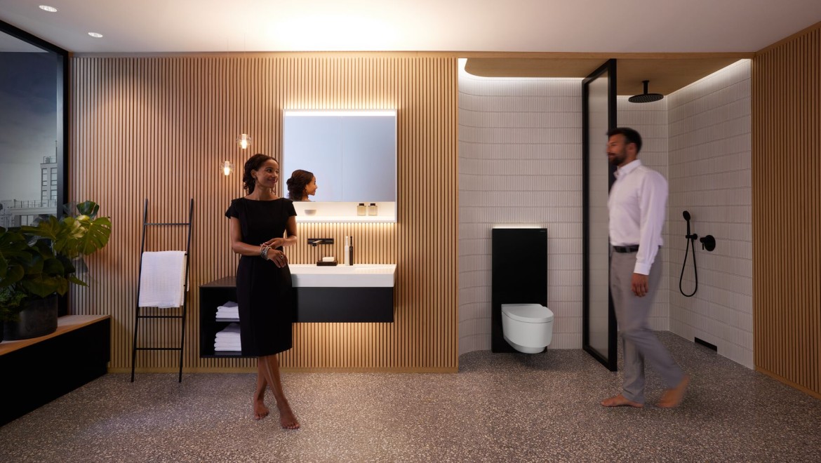 Mand og kvinde i perfekt oplyst badeværelse med Geberit ONE-produkter