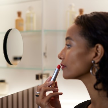 En kvinde bruger et spejl til at lægge makeup