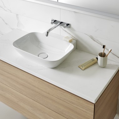 Hvid håndvask og bordplade kombineret med et badeværelsesmøbel i træ (© Geberit)