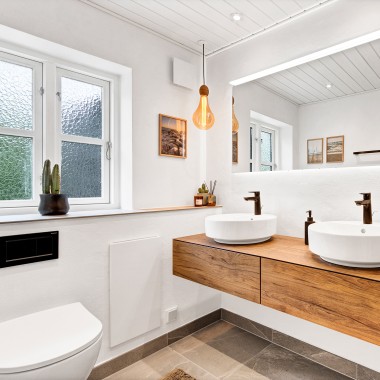 Lyst, renoveret badeværelse med to runde håndvaske, stort spejl og badeværelsesmøbel i træ (© @triner2 and @strandparken3)