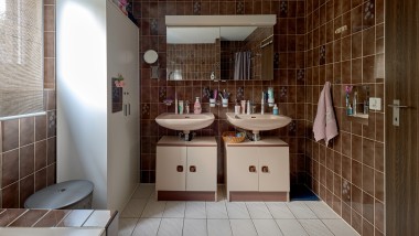 Badeværelse med brune klinker og to håndvaske