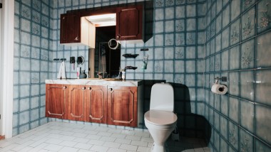 Badeværelse med blå klinker og gulvstående toilet