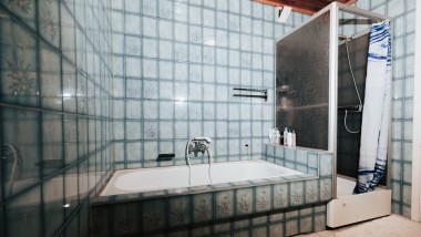 Badeværelse med blå klinker, bruseniche og badekar