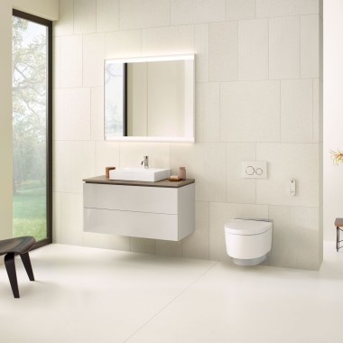 Beige badeværelse med spejlskab, håndvask, bettjeningsplade og et douchetoilet fra Geberit. 