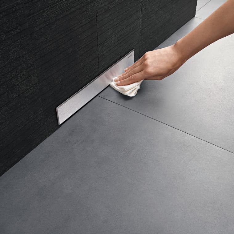 Hånd rengør dækpladen på et Geberit vægafløb Hånd rengør dækpladen på et Geberit vægafløb